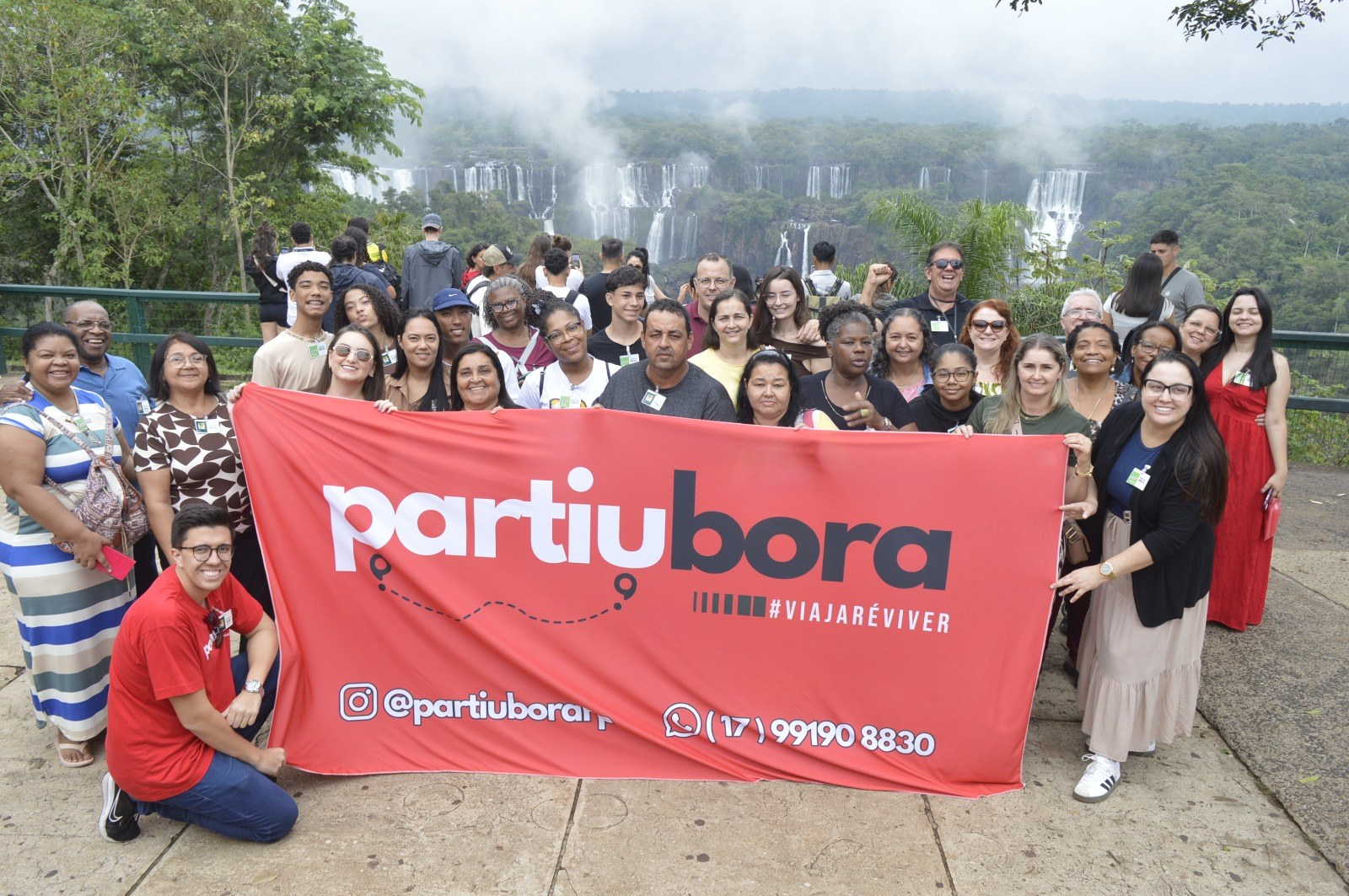 Grupo PartiuBora com faixa da marca nas Cataratas do Iguaçu